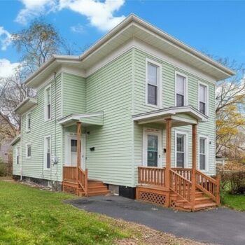 A green two-family house with twin porches on Marcellus Street, Syracuse